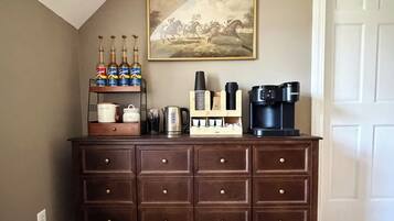 Eine Küchenarbeitsplatte mit Kaffeemaschine, Kaffeemühle und einer Ablage mit Flaschen.