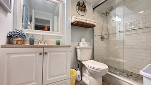 Un baño con inodoro, lavabo, espejo y zona de ducha.