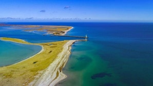 An aerial view of a coastal area with a lighthouse, clear blue waters, and a sandy beach. - Houseboat in Olpenitz With Swimming Pool (Kappeln)