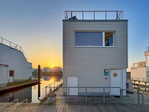 Un edificio moderno con techo plano, un ventanal grande y una puerta pequeña.