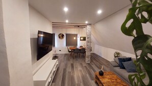 Un salon moderne doté d’un téléviseur à écran plat, d’un coin repas et d’un espace salon confortable avec une table basse.