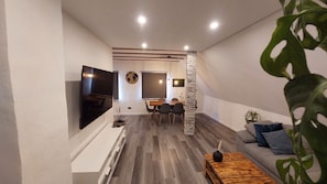 Una sala moderna con televisor de pantalla plana, zona de comedor y un rincón de estar acogedor con una mesita de centro.