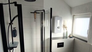 Une salle de bain moderne avec une douche à parois de verre, des toilettes et une fenêtre.