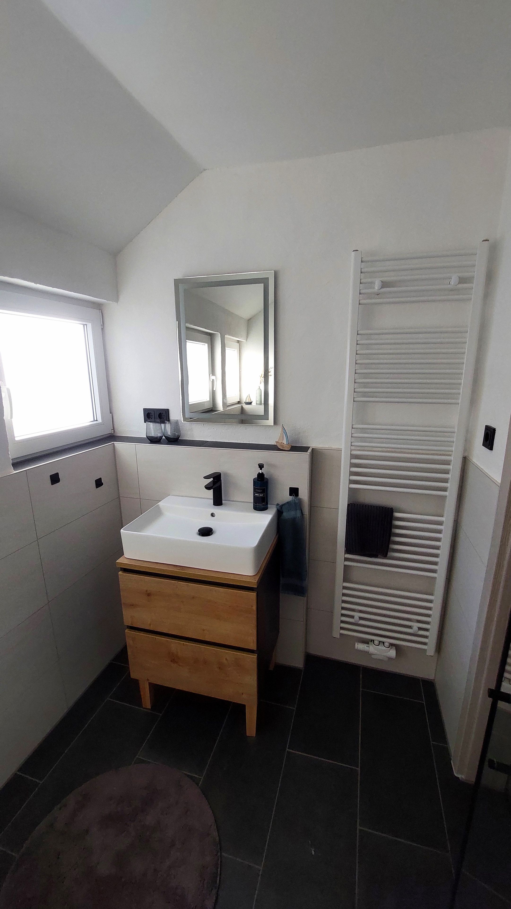 Un baño moderno con lavamanos, espejo y toallero blancos.
