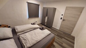 Un dormitorio con dos camas, un armario y una puerta.