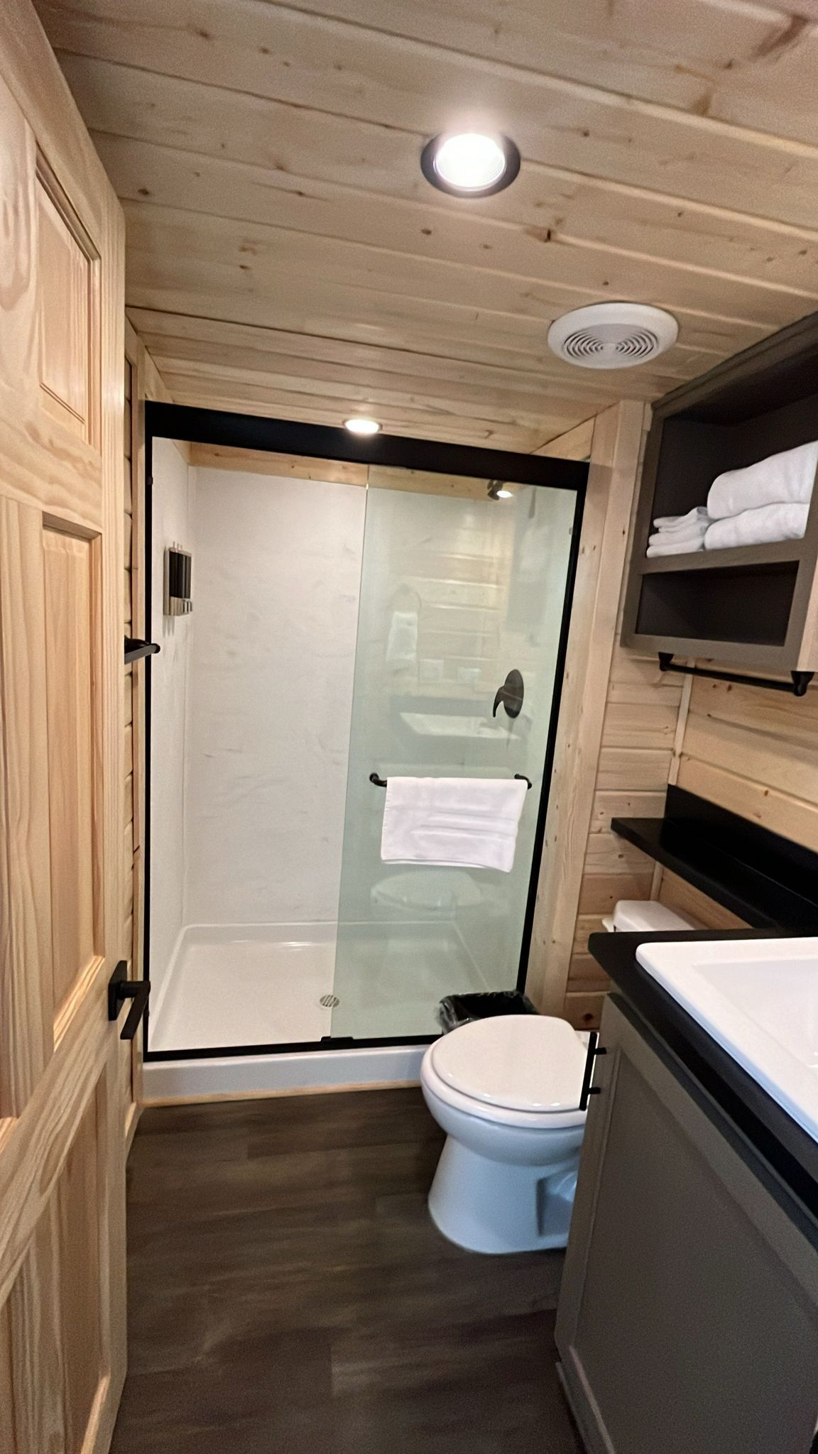A compact bathroom with a glass shower enclosure, a toilet, and a sink with a countertop.