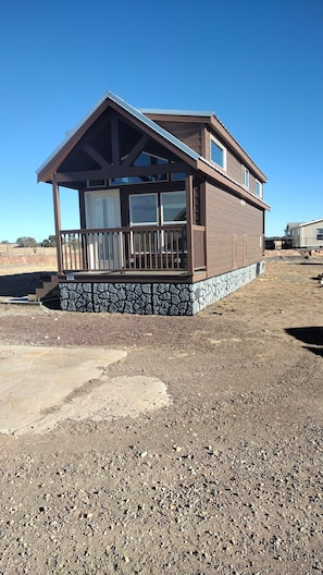 Ein zweistöckiges Gebäude mit steinernen Fundament und einer Holzterrasse.