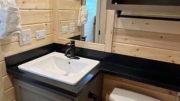 A compact bathroom with a white sink, black countertop, and a white toilet.