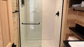 A compact bathroom with a glass-enclosed shower, a toilet, and a sink.