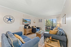 A living room with two sofas, a coffee table, a TV, and a wall-mounted star decoration. - Mariner's Cove 230C-2BR Condo in Shore Drive (Myrtle Beach)