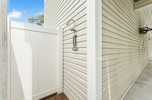 Un mur extérieur blanc, agrémenté d’une rambarde en métal et d’une clôture blanche.