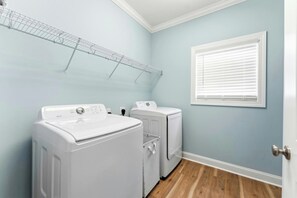 A laundry room with two white washing machines, a drying rack, and a window with blinds. - 4BR Hillside Haven Located in Crescent Beach (North Myrtle Beach)