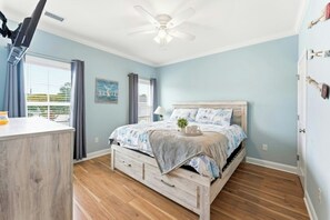 A bedroom with a bed, a ceiling fan, a window with curtains, and a wooden floor. - 4BR Hillside Haven Located in Crescent Beach (North Myrtle Beach)
