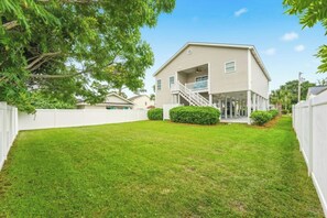 A two-story house with a front porch, a staircase, and a well-maintained lawn. - 4BR Hillside Haven Located in Crescent Beach (North Myrtle Beach)