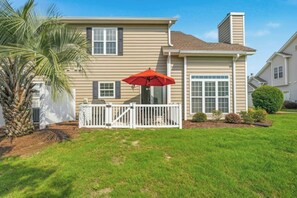 A two-story house with a front deck, a palm tree, and a red umbrella. - Fairway Oaks 44C-Cherry Grove 3BR- Community Pool (North Myrtle Beach)