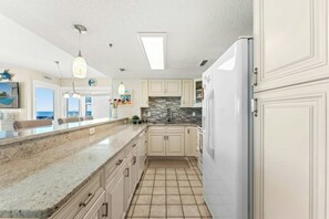 A kitchen with white cabinets, a granite countertop, and a tiled backsplash. - Crescent Towers II 508-Oceanfront Corner Unit-2BR (North Myrtle Beach)