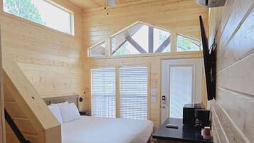 A compact cabin with a bed, a small kitchenette, and a ceiling fan.