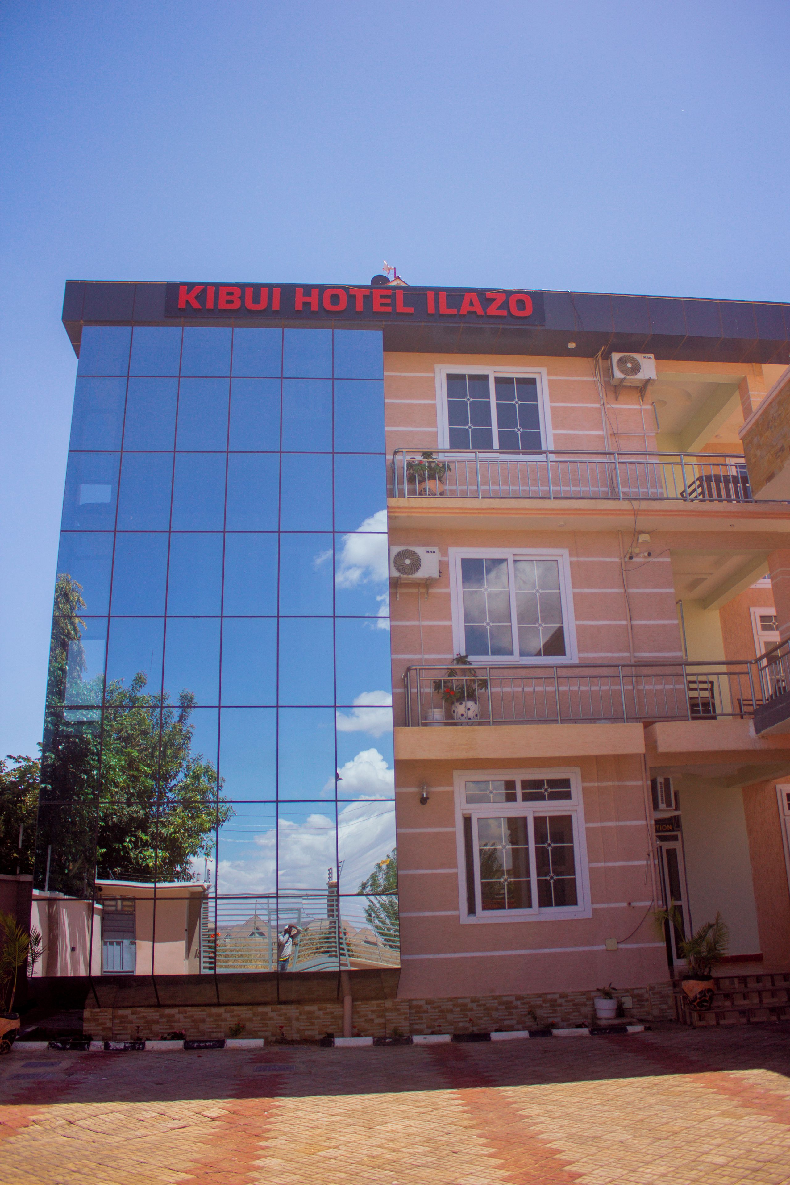 Un hotel con fachada de vidrio moderna y un letrero que dice 'KIBUI HOTEL ILAZO'.