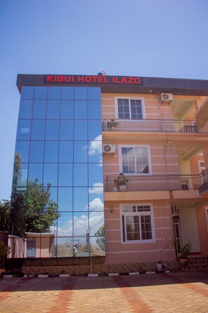 Hotel com fachada de vidro moderna e placa com a inscrição 'KIBUI HOTEL ILAZO'.