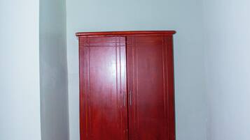 A room with a wooden wardrobe, a patterned sofa, and a light-colored wall.