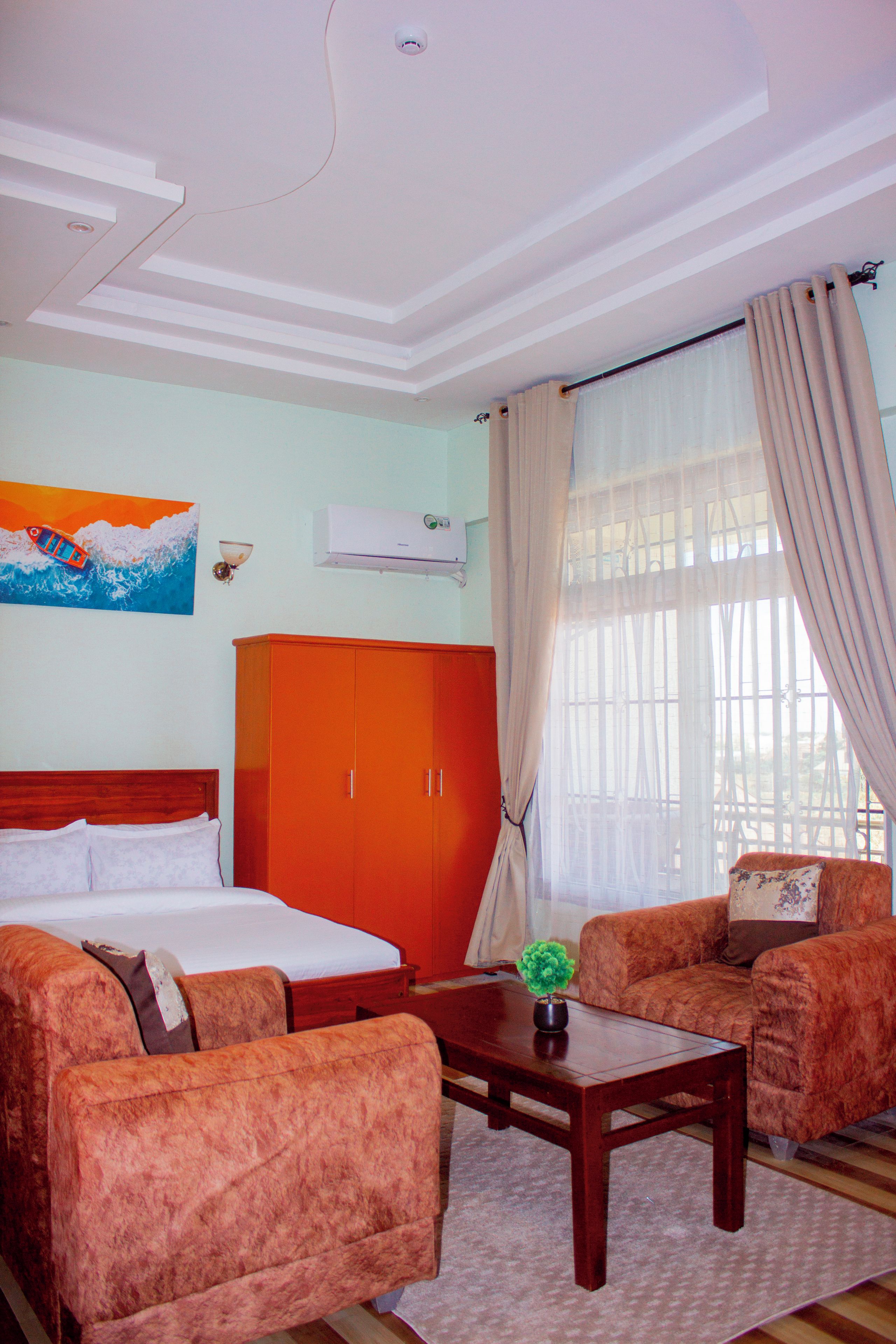 Una habitación de hotel con una cama, un sofá, una mesa de centro y un cuadro en la pared.