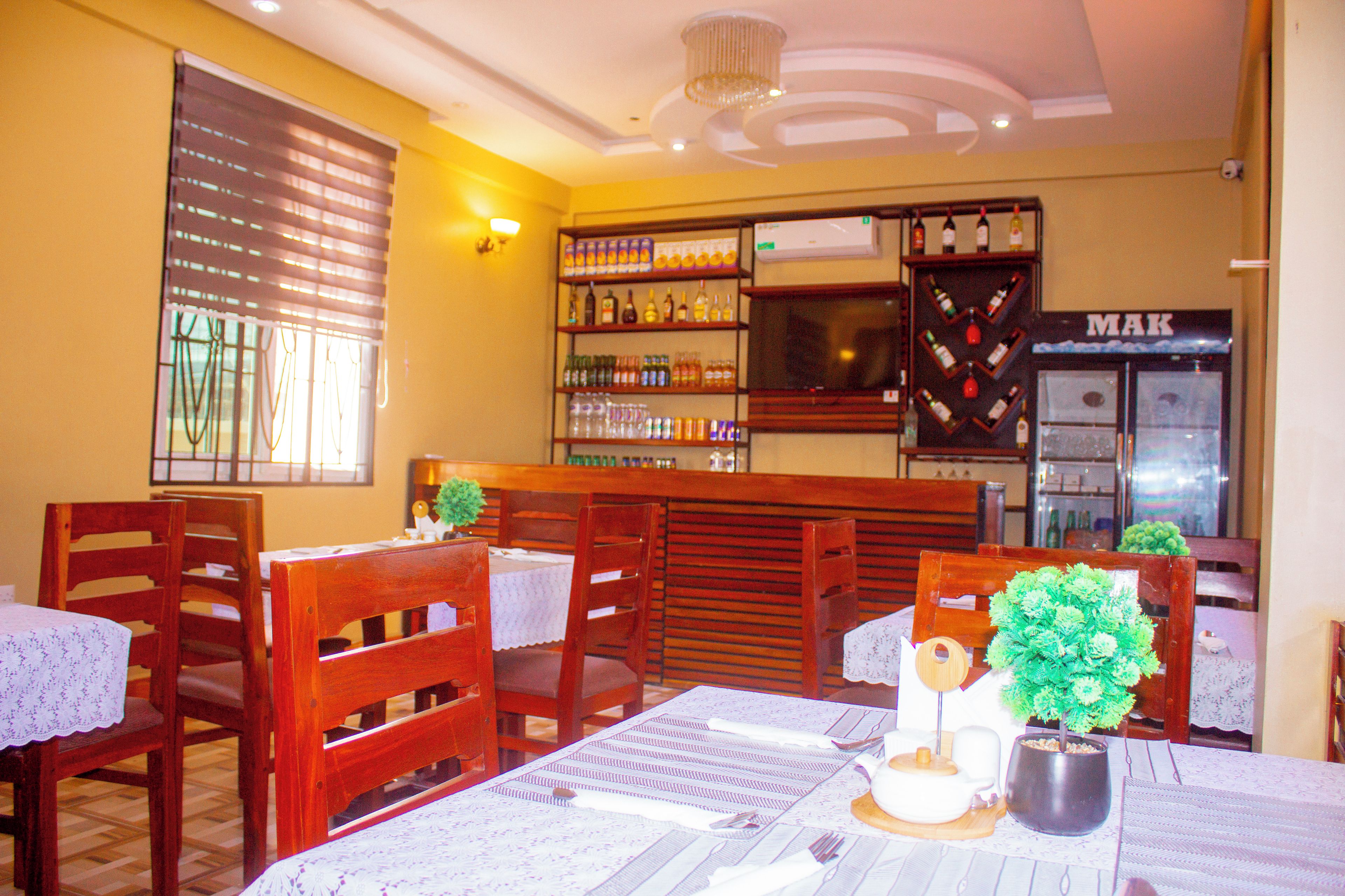 Interior de un restaurante con sillas de madera, una zona de bar y un refrigerador con la etiqueta 'MAK'.
