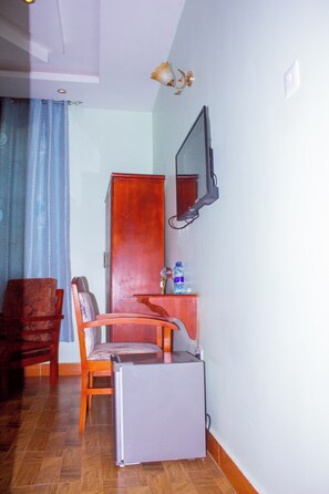 A room with a desk, chair, and a small refrigerator. - Kibui Hotel Ilazo (Dodoma)
