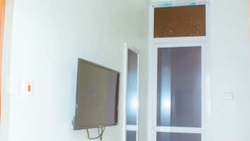 A room with a mounted air conditioner, a television on the wall, and a sliding glass door.