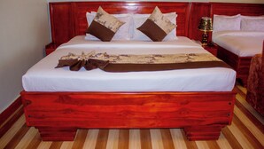 A large bed with a wooden frame, white bedding, and two decorative pillows. - Kibui Hotel Ilazo (Dodoma)