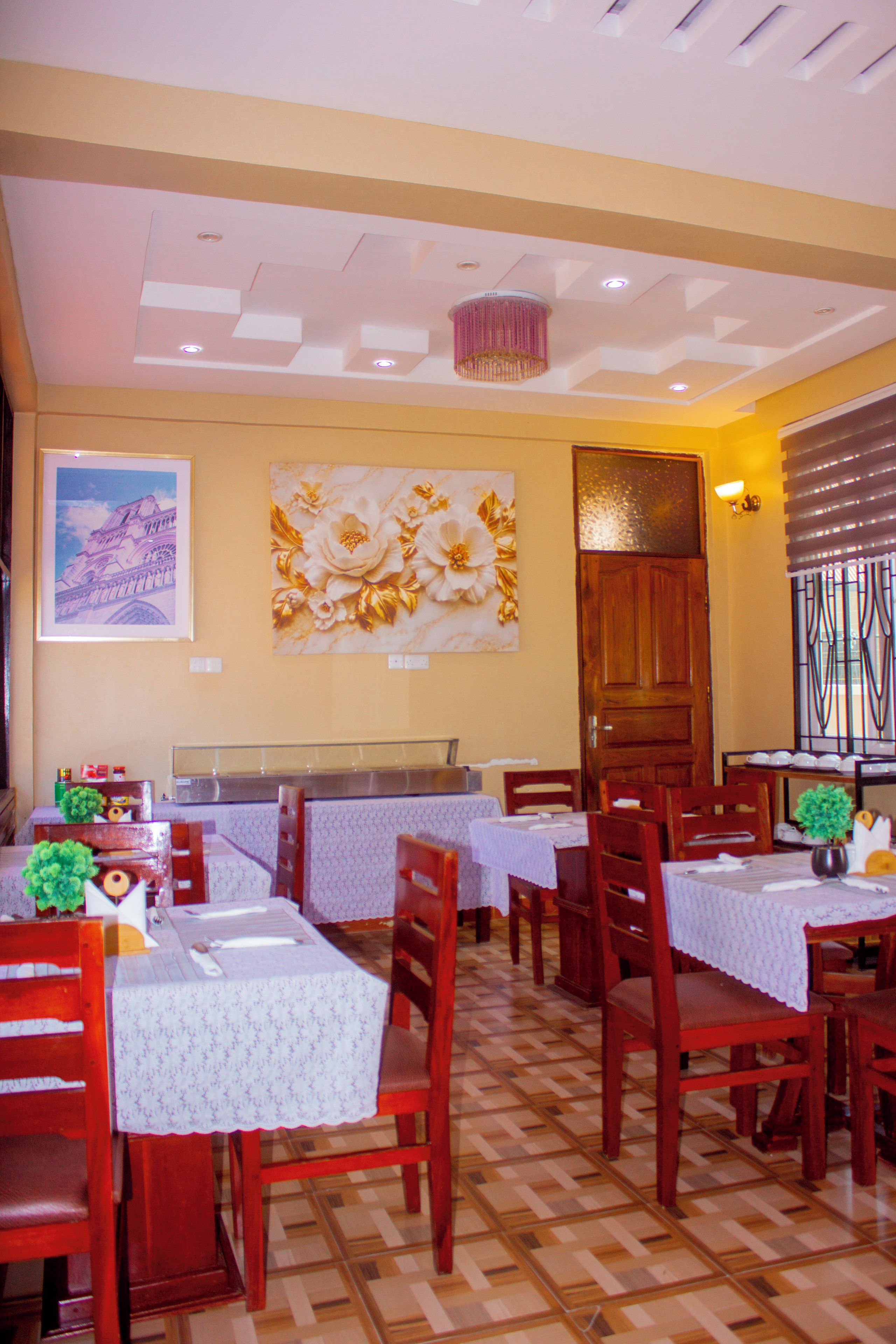 A restaurant interior with multiple tables, chairs, and a decorative wall piece.
