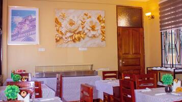 A restaurant interior with multiple tables, chairs, and a decorative wall piece.