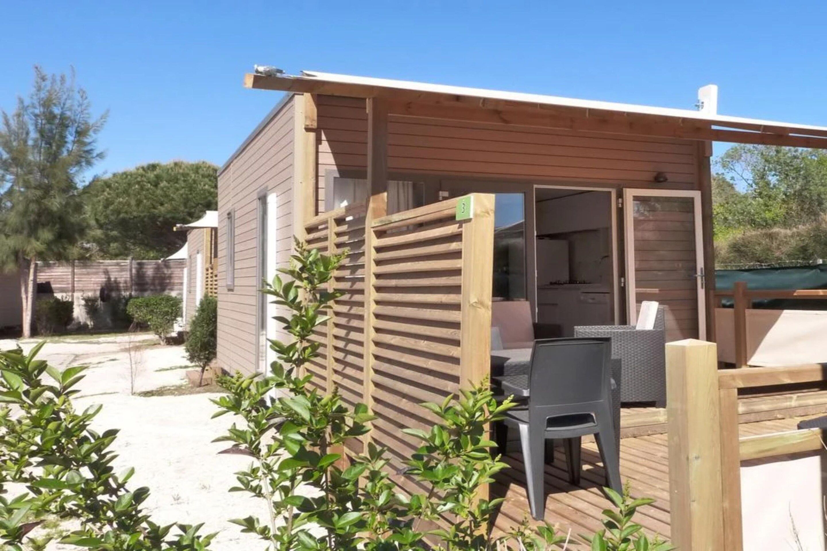 Een houten chalet met een patio, een stoel en een tafel.