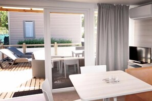 A modern outdoor living space with a sliding glass door, a white table, and a sofa. - Hyeres Stay Near the Beach (Hyères)