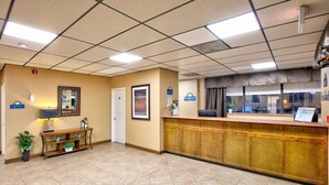 A reception area with a reception desk, a small seating area with a bench and plants, and a door leading to other rooms. - Top 10 Clash! Days Inn Batesville. Room with 2 Double Beds. (Batesville)