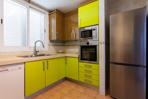 Eine Küche mit einem Edelstahlkühlschrank, einer Bosch-Mikrowelle und einem Waschbecken mit modernem Wasserhahn.