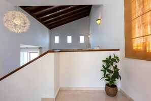 A staircase with a wooden handrail, a potted plant, and a hanging light fixture. - Todimer Luxury Villa Herradura (Almuñécar)