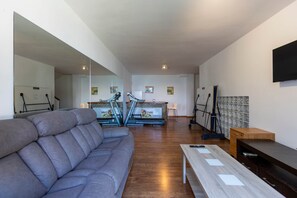 A spacious living area with a grey sofa, a wooden coffee table, and a TV mounted on the wall. - Todimer Luxury Villa Herradura (Almuñécar)