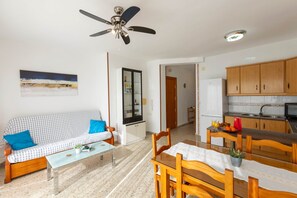 A living room with a sofa, coffee table, and a dining area with chairs and a table. - Todimer Neptuno Beach (Torrenueva Costa)
