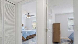 Une chambre à coucher avec un lit, un ventilateur de plafond, une armoire et une fenêtre avec des stores.