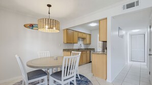 Un coin repas avec une table ronde, des chaises blanches et un luminaire suspendu.