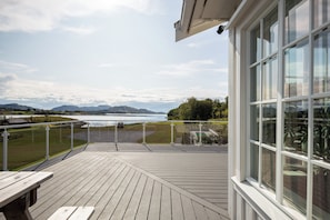 A wooden deck with a view of a lake and mountains. - Unique property with its own beachfront for rent - Kystperlen Lysøysundet (Trøndelag)