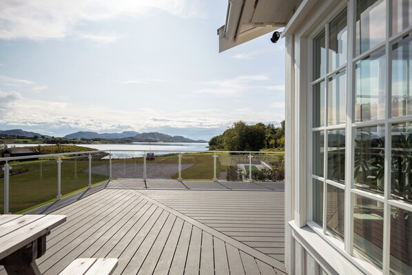 A wooden deck with a view of a lake and mountains.