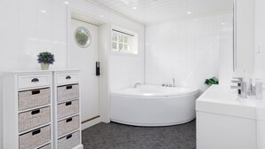 Une salle de bain moderne avec une baignoire sur pieds, un grand miroir et un meuble blanc avec des tiroirs.