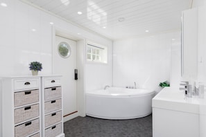 Une salle de bain moderne avec une baignoire sur pieds, un grand miroir et un meuble blanc avec des tiroirs.