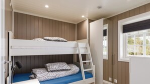 Une chambre avec un lit superposé, un bureau, une échelle et une fenêtre.