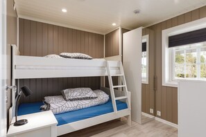 Une chambre avec un lit superposé, un bureau, une échelle et une fenêtre.