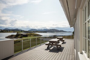 Une terrasse avec des tables de pique-nique offrant une vue sur un lac et des montagnes.