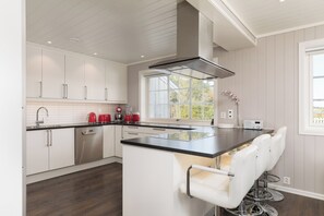 A modern kitchen with white cabinetry, a black countertop, and a built-in island with bar stools.