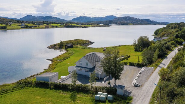 Une propriété située au bord d’un lac, comprenant une maison, une allée en gravier et un espace de stationnement.