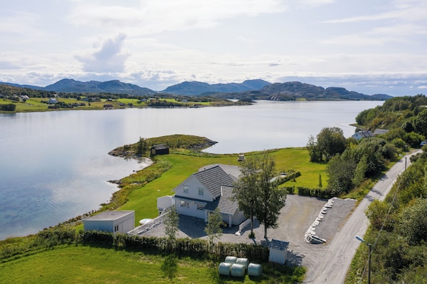 Une propriété située au bord d’un lac, comprenant une maison, une allée en gravier et un espace de stationnement.